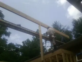 Carpenter setting a ridge beam over a new addition frame — Ice Dam Removal by Roofing Brothers in Ronald