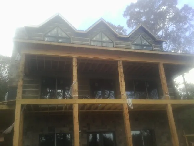 Dormers and porch framing on a large log home under construction — Roof Coating work by our crew in Ronald