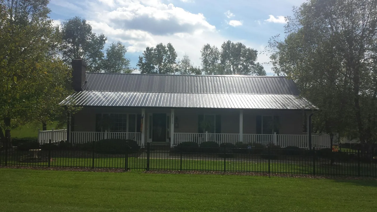 Gray metal roof on a brick ranch with a full width front porch — Gutter Guard Installation work by our crew in Ronald